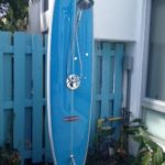 Outdoor shower installed on a blue surfboard